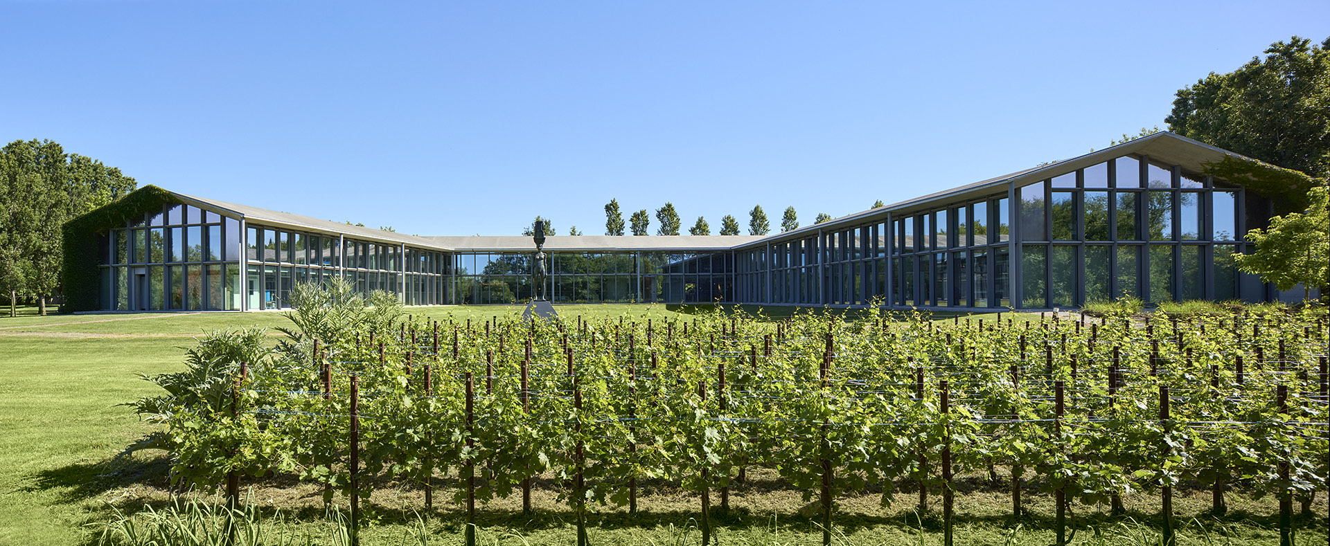 Il campus di Roncade di giorno, una scultura sul prato sotto un cielo limpido.